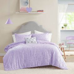 a bed with purple comforter and pillows in a bedroom