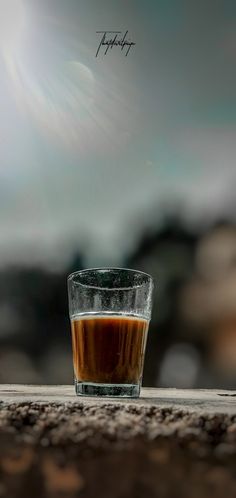 a shot glass filled with liquid sitting on top of a wooden table next to rocks