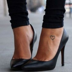 a woman's foot with a small heart tattoo on her left ankle and heel