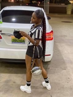 a girl in black and white uniform walking next to a car