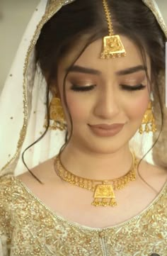 a woman in a bridal outfit with gold jewelry on her head and eyes closed