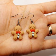 a pair of gingerbread man earrings on a person's hand