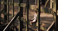 a person standing on top of a wooden fence with their feet in the gated area