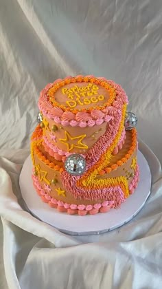 a three tiered cake with pink and yellow frosting