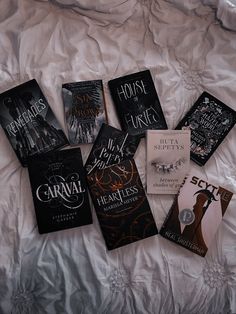 six books laid out on a bed with white sheets