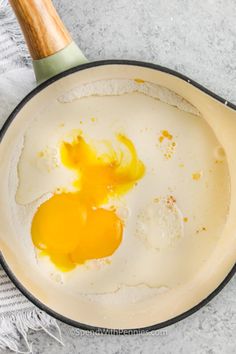 two eggs are being cooked in a frying pan on a towel next to a wooden spatula