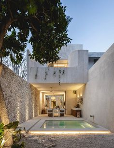 an outdoor swimming pool in the middle of a house with stone walls and trees around it