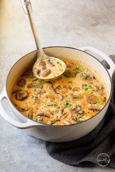 a large pot filled with food on top of a counter next to a wooden spoon