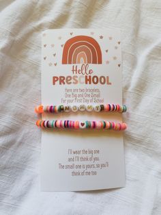 two bracelets on top of a white sheet with a card saying hello pre - hool