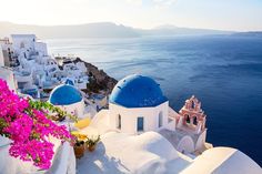 an image of a beautiful view of the ocean and some white buildings with blue domes