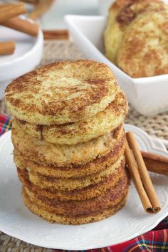 stack of cinnamon spiced pancakes on a white plate with cinnamon sticks in the background