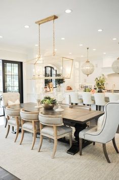 a dining room table with chairs and a chandelier hanging from it's ceiling