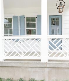 a white house with blue shutters and a red fire hydrant on the front porch