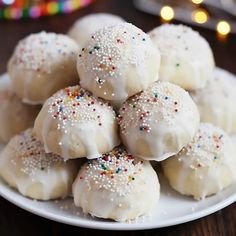 a white plate filled with cookies covered in sprinkles on top of a wooden table