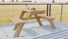 a wooden picnic table sitting on top of a metal deck next to a grassy field