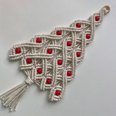 a white and red piece of art with tassels