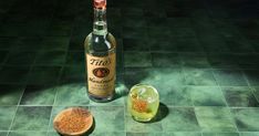 a bottle of liquor sitting on top of a green tiled floor next to a wooden spoon