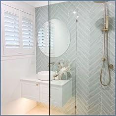 a bathroom with a walk in shower next to a white sink and mirror on the wall