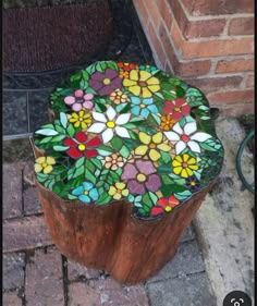 a wooden stump with stained glass flowers on it sitting in front of a brick wall