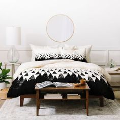 a bed with black and white comforter in a bedroom next to a coffee table