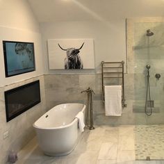 a bathroom with a large tub, shower and pictures on the wall above it's glass doors