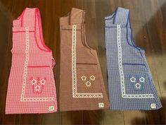 three vests are lined up on the floor, one is red and blue with white designs