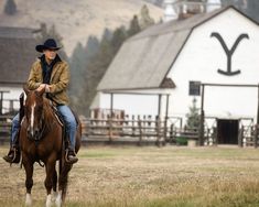 a man riding on the back of a brown horse in front of a white building