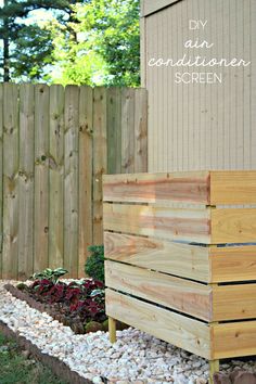 a wooden planter sitting next to a fence in front of a house with gravel