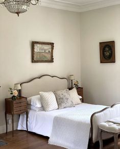 a bedroom with a bed, dresser and chandelier