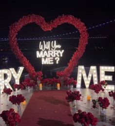 a red carpeted aisle with flowers and lighted letters that read will you marry me?