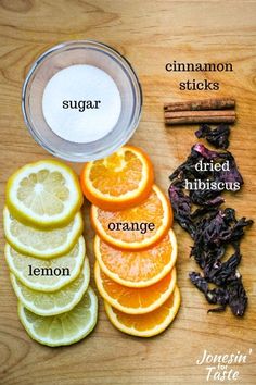 orange slices, lemons, cinnamon sticks, and sugar on a table with ingredients