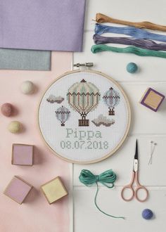 a cross - stitch hot air balloon is on the table next to some crafting supplies