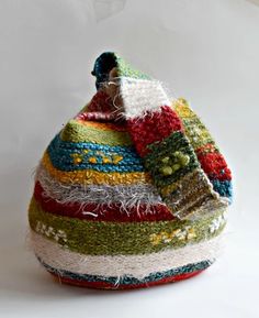 a multicolored hat is sitting on a white surface and it's made out of yarn