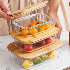 two clear containers with wooden lids are stacked on top of each other and filled with fruit