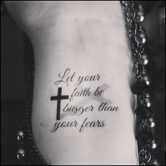 a cross tattoo on the side of a woman's stomach with words written in black ink