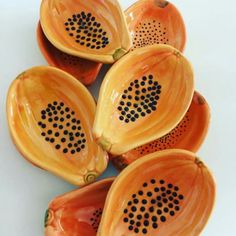 four orange bowls with holes in them on a white surface