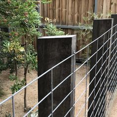 the fence is made of black wood and metal bars, with trees in the background