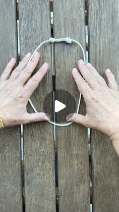 two hands holding an object on top of a wooden table next to another person's hand