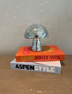 two books stacked on top of each other next to a small lamp that is shaped like a mushroom