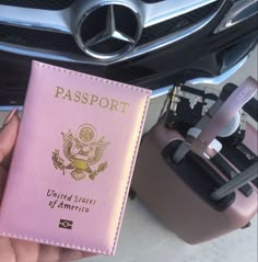 a person holding a pink passport in front of a car