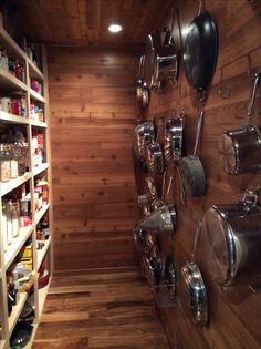 a wooden pantry with pots and pans hanging on the wall next to shelves full of cooking utensils