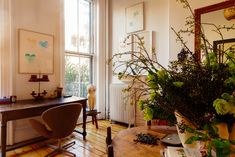 a living room filled with furniture and a wooden table next to a large vase full of flowers