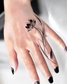 a woman's hand with a black and white flower tattoo on the middle finger