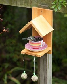 a bird feeder hanging from the side of a wooden fence