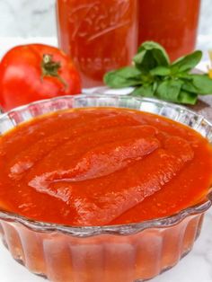 tomato sauce in a glass dish next to tomatoes and basil