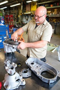 a man is working on an engine in a garage with other tools and equipment around him