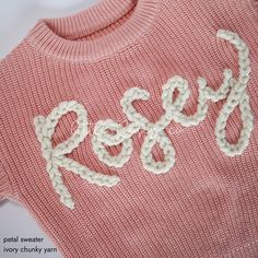 a pink sweater with the word rosy written on it