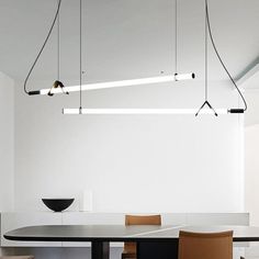 a dining room table with chairs and lights hanging from the ceiling