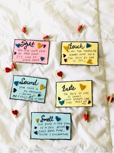 four pieces of paper with words and hearts attached to them on a sheet of white fabric