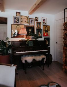 a living room with a piano and many pictures on the wall above it's fireplace